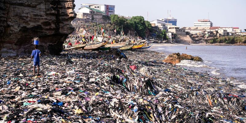 Ein Sandstrand, dessen Sand gar nicht mehr zu sehen ist: Massen an Klamotten vermüllen diesen Küstenabschnitt von Accra.  - Foto: Kevin McElvaney/Deutsche Umwelthilfe/dpa