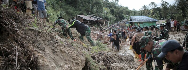 Rettungskräfte und Dorfbewohner beseitigen Schlamm. - Foto: Gatha Ginting/XinHua/dpa