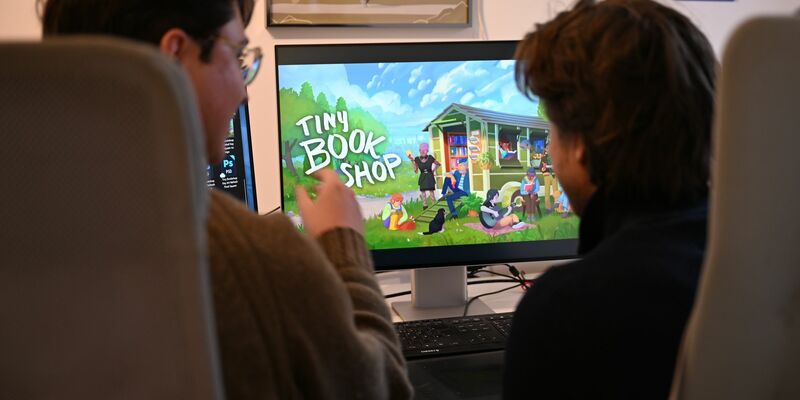 Als Bachelor-Arbeit an der Uni entstanden, inzwischen ein großer Verkaufserfolg: Das Spiel «Tiny Bookshop» mit ihren beiden Entwicklern David Zapfe-Wilde (links) und Raven Rusch.  - Foto: Wolf von Dewitz/dpa