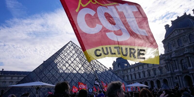 Angestellte zeigen Fahnen der Gewerkschaft CGT vor dem Louvre. - Foto: Michel Euler/AP/dpa
