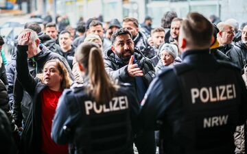 Aufgebrachte Kunden diskutieren vor der Sparkassenfiliale mit Polizeibeamten (Archivfoto) - Foto: Christoph Reichwein/dpa