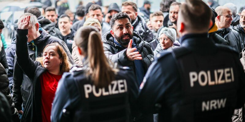 Aufgebrachte Kunden diskutieren vor der Sparkassenfiliale mit Polizeibeamten (Archivfoto) - Foto: Christoph Reichwein/dpa