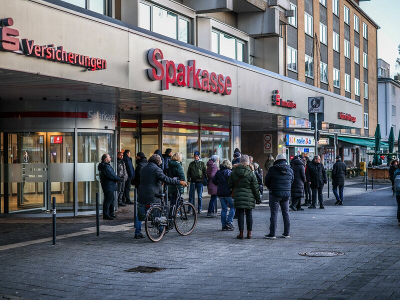 Nach einem Einbruch in den Tresorraum einer Bankfiliale in Gelsenkirchen warten Menschen vor dem Eingang auf Informationen. - Foto: Christoph Reichwein/dpa