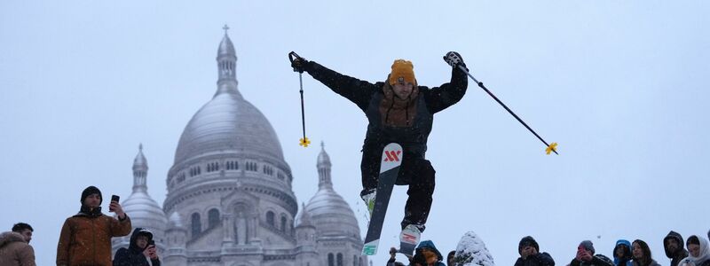 Ein Mann springt mit seinen Skiern den Hügel bei der Basilika Sacre-Coeur im französischen Paris hinunter. - Foto: Aurelien Morissard/AP/dpa