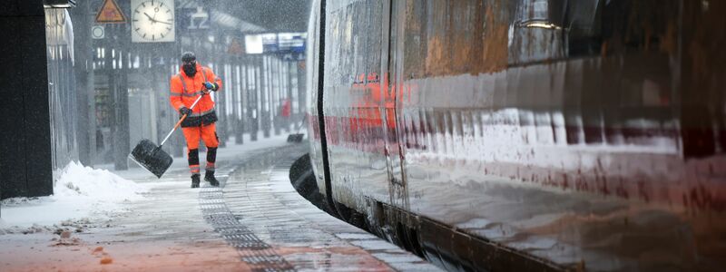 Mitarbeiter schieben Schnee von einem Bahnsteig am Hamburger Hauptbahnhof. - Foto: Christian Charisius/dpa