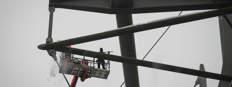 Arbeiter mit einem Hubsteiger entfernen Eis und Schnee von den Trägern des Stadiondachs in Hamburg. - Foto: Christian Charisius/dpa