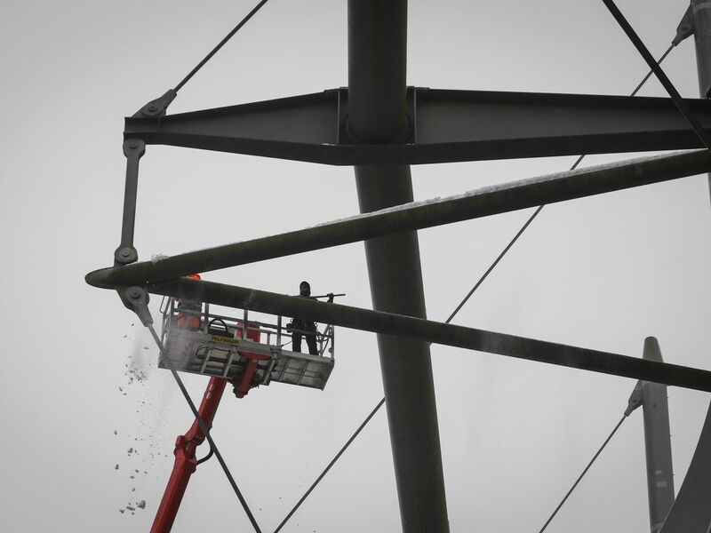 Arbeiter mit einem Hubsteiger entfernen Eis und Schnee von den Trägern des Stadiondachs in Hamburg. - Foto: Christian Charisius/dpa