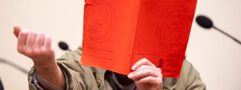 Der Angeklagte verdeckte sein Gesicht zum Prozessauftakt zunächst mit einer Mappe. - Foto: Peter Kneffel/dpa