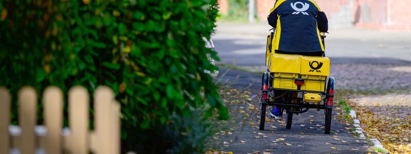 Ein Briefträger bei der Arbeit - jedes Jahr werfen Postler Milliarden von Briefen in Briefkästen ein. - Foto: Philipp Schulze/dpa