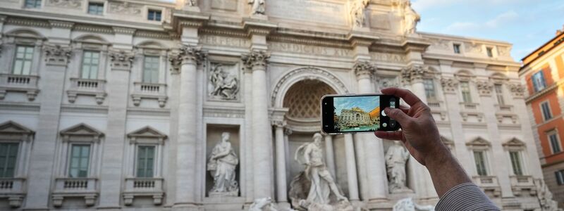 Ein Besucher macht ein Foto des Trevi-Brunnens. (Archivbild) - Foto: Andrew Medichini/AP/dpa