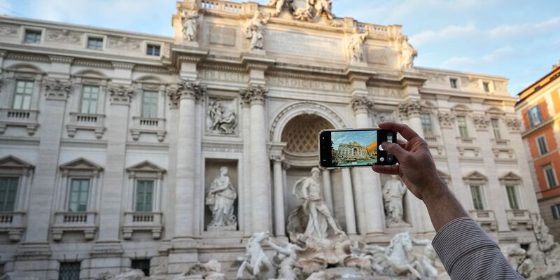 Ein Besucher macht ein Foto des Trevi-Brunnens. (Archivbild) - Foto: Andrew Medichini/AP/dpa