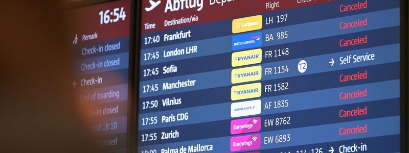 Passagiere blicken auf eine Anzeigetafel am Hauptstadtflughafen BER. - Foto: Michael Bahlo/dpa