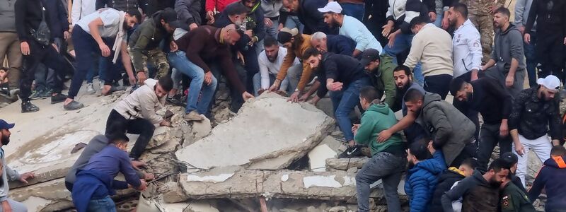 Rettungskräfte und Anwohner suchen nach Überlebenden in den Trümmern eines eingestürzten Gebäudes. - Foto: Uncredited/AP/dpa