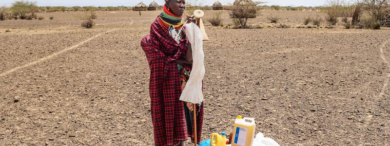 Eine Frau steht in Kenia neben einer Lebensmittelration des Welternährungsprogramms (WFP). - Foto: Patrick Ngugi/AP/dpa