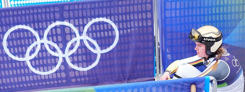Emma Aicher sitzt nach ihrem Aus im Super-G frustriert im Zielbereich von Cortina d'Ampezzo. - Foto: Michael Kappeler/dpa