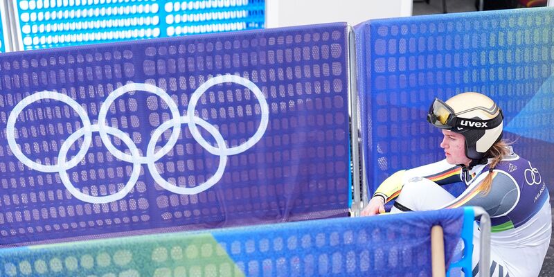 Emma Aicher sitzt nach ihrem Aus im Super-G frustriert im Zielbereich von Cortina d'Ampezzo. - Foto: Michael Kappeler/dpa