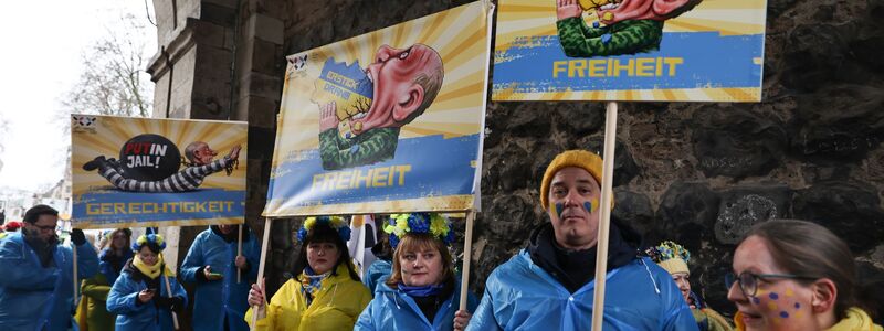 Mitglieder des ukrainischen Hilfsvereins Blau-Gelbes Kreuz halten im Kölner Rosenmontagszug Plakate mit früheren Putin-Darstellungen aus den Zügen in Köln und Düsseldorf hoch.    - Foto: Oliver Berg/dpa