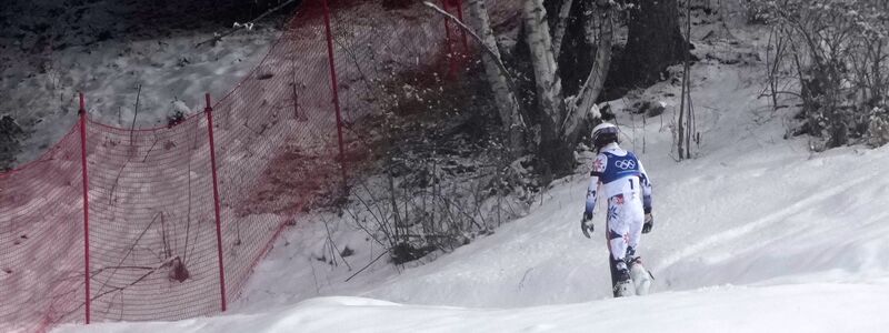 Ein Bild dieser Winterspiele: Atle Lie McGrath stapfte nach seinem Aus im Slalom einsam durch den Schnee in Richtung eines Waldstück. - Foto: John Locher/AP/dpa