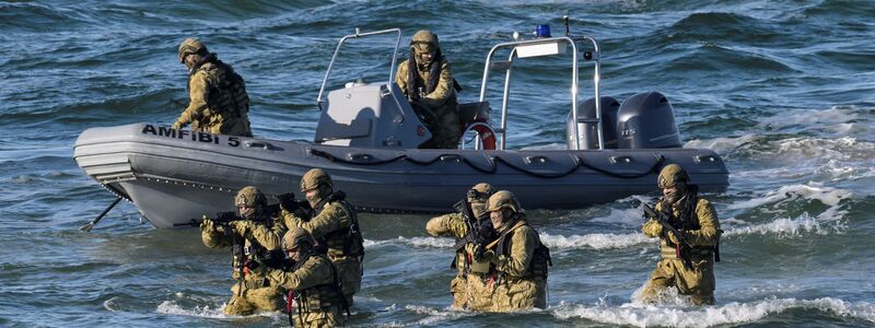 Taucher machen den Anfang und steigen aus dem Wasser auf den schneebedeckten Strand, um den Küstenabschnitt zu sichern. - Foto: Fabian Bimmer/Reuters/Pool/dpa