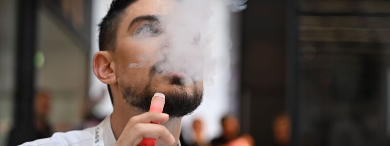 Ein Verkäufer einer E-Zigaretten-Firma nutzt bei der Dortmunder Messe Intertabac demonstrativ eine E-Zigarette. Der Verkauf dieser Produkte boomt. (Archivbild) - Foto: Wolf von Dewitz/dpa