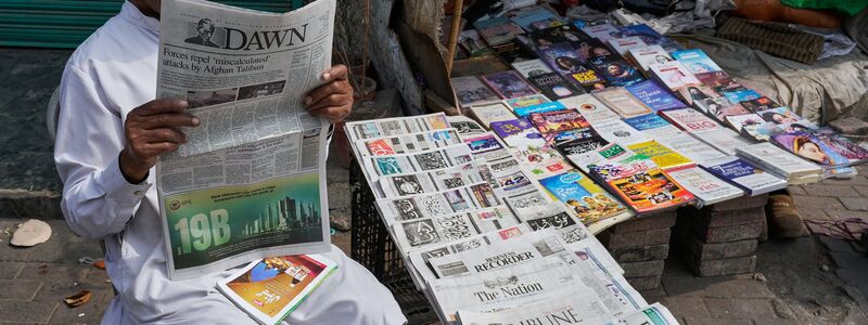 Ein Pakistaner liest an einem Verkaufsstand eine Morgenzeitung, die über die nächtlichen grenzüberschreitenden Kämpfe zwischen pakistanischen und afghanischen Streitkräften berichtet. - Foto: K.M. Chaduary/AP/dpa