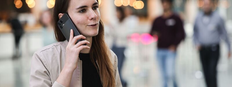 Die für KI zuständige Telekom-Mitarbeiterin Lena Drubel führt bei einer Testvorführung des KI-Assistenten ein Handytelefonat. - Foto: Oliver Berg/dpa