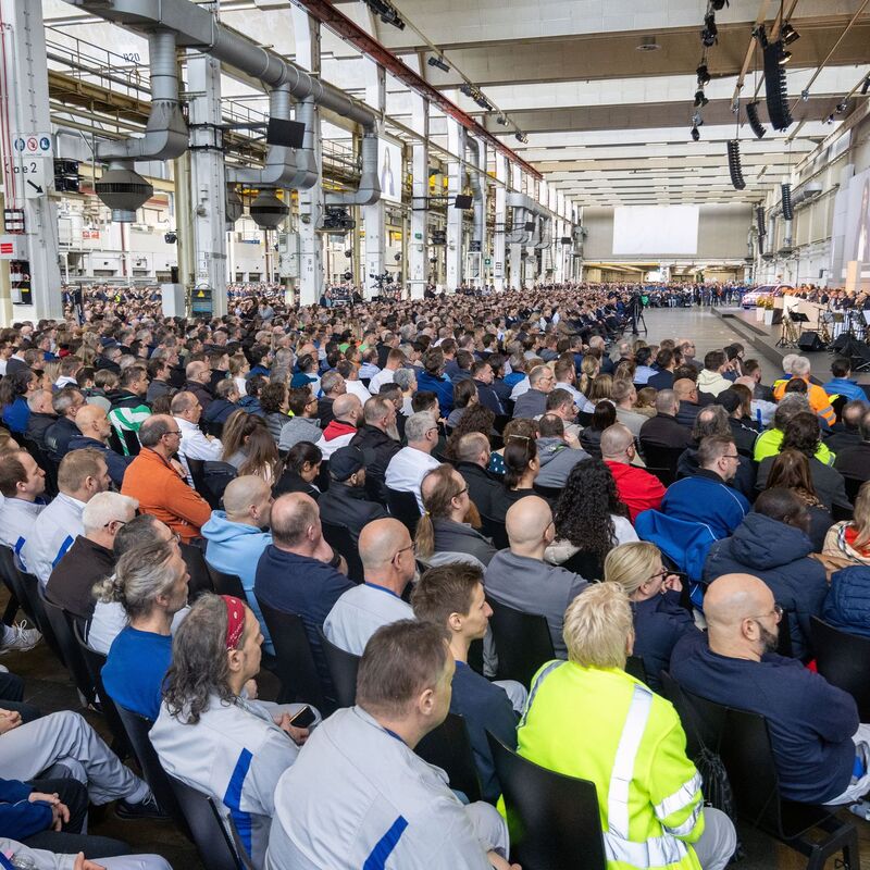 Tausende Mitarbeiterinnen und Mitarbeiter folgen der Versammlung in Halle 11 des Stammwerks. - Foto: Kevin Nobs/Volkswagen AG/dpa