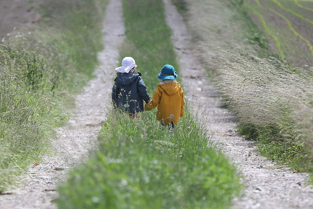 Zwei kleine Kinder laufen auf einem Feldweg (Archiv)