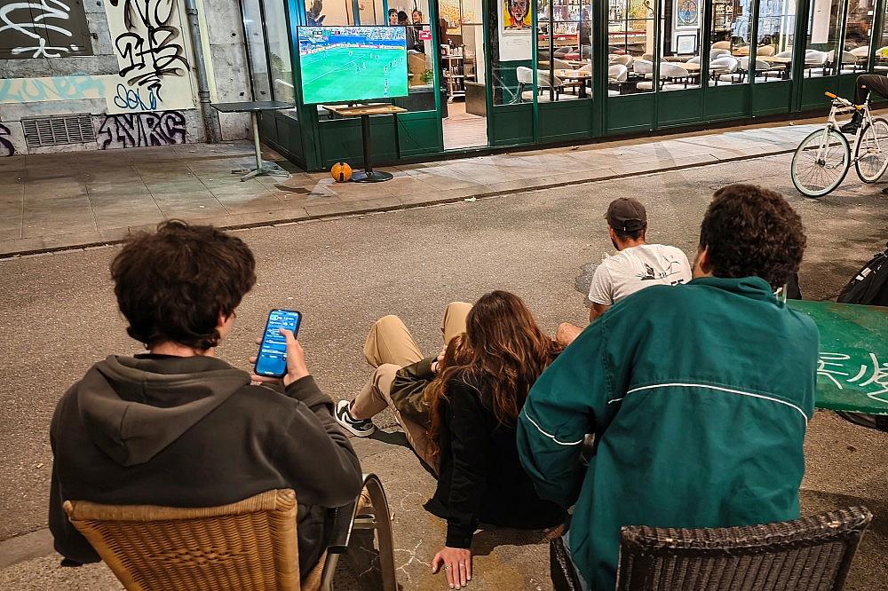 Interessierte schauen nachts auf der Straße Fußball-WM 2026 via dts Nachrichtenagentur