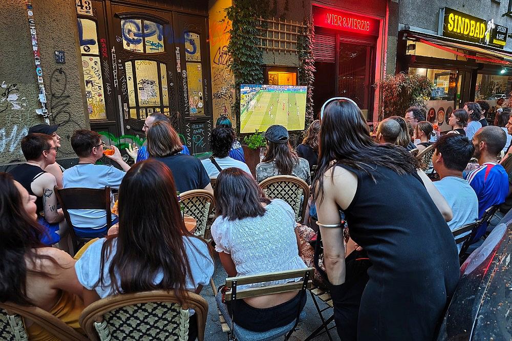 Interessierte schauen auf der Straße Fußball am 26.06.2026