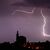 Blitze entladen sich aus einer Gewitterwolke über der Pfarrkirche im bayrischen Straubing. - Foto: Armin Weigel/dpa