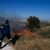 Ein Feuerwehrhubschrauber wirft Wasser auf die Flammen nahe des Militärstützpunkts Kapota im Gebirge Parnitha. - Foto: Thanassis Stavrakis/AP/dpa