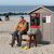 Ein Mann sitzt am Ostseestrand vor dem Häuschen eines Strandkorbvermieters und genießt das warme und sonnige Wetter. - Foto: Bernd Wüstneck/dpa