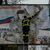 Ein ukrainischer Feuerwehrmann reißt in der kürzlich befreiten Stadt Cherson ein russisches Werbeplakat von einer Werbetafel. - Foto: Bernat Armangue/AP/dpa