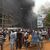Mit dem brennenden Hauptquartier der Regierungspartei im Rücken demonstrieren Anhänger meuternder Soldaten in der Hauptstadt Niamey. - Foto: Fatahoulaye Hassane Midou/AP/dpa