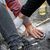 Eien Aktivistin der Letzten Generation hat sich auf die Straße geklebt. Ein Polizist versucht, ihre Hand vom Asphalt zu lösen. - Foto: Fabian Sommer/dpa